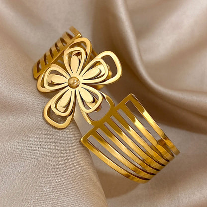 Shiny gold hair cuff with floral centerpiece and open comb-like sides, displayed diagonally.