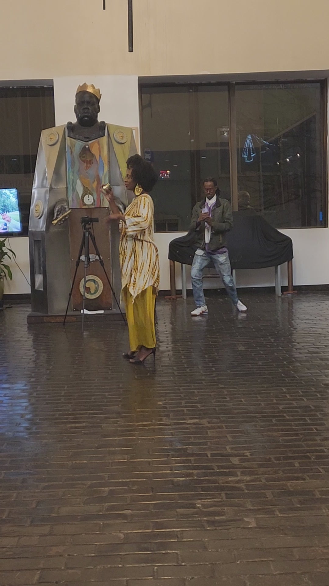 Woman wearing a Shark Hem Top Pants Set in mustard yellow with a tie-dye pattern, standing in front of a statue indoors.