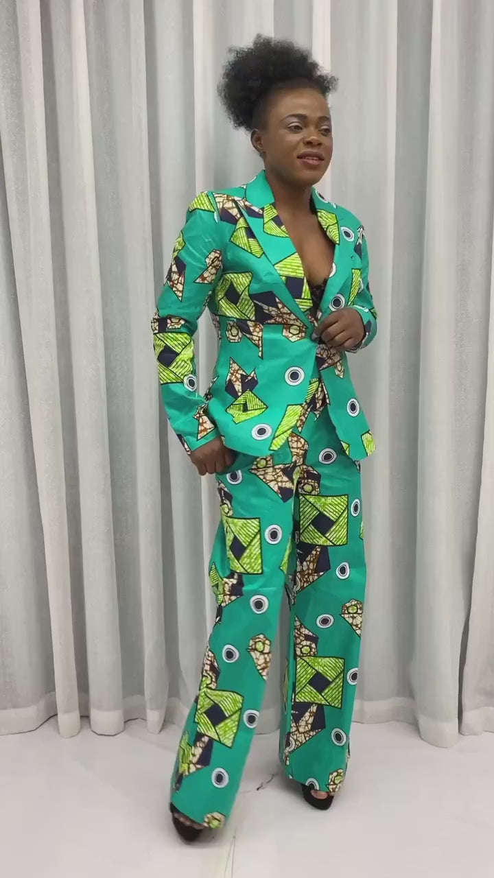 Woman wearing a green African pantsuit with bold prints. The outfit includes a fitted jacket and wide-leg trousers, ideal for stylish occasions.