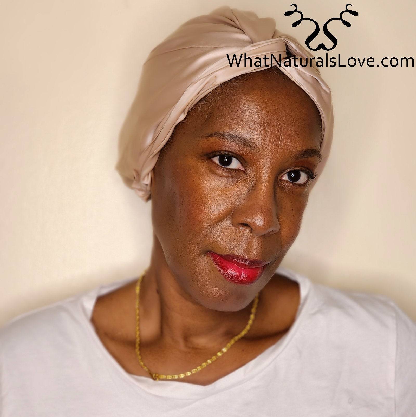 Close-up of a woman wearing a beige silk bonnet from What Naturals Love. Helps protect locs and maintain moisture overnight.
