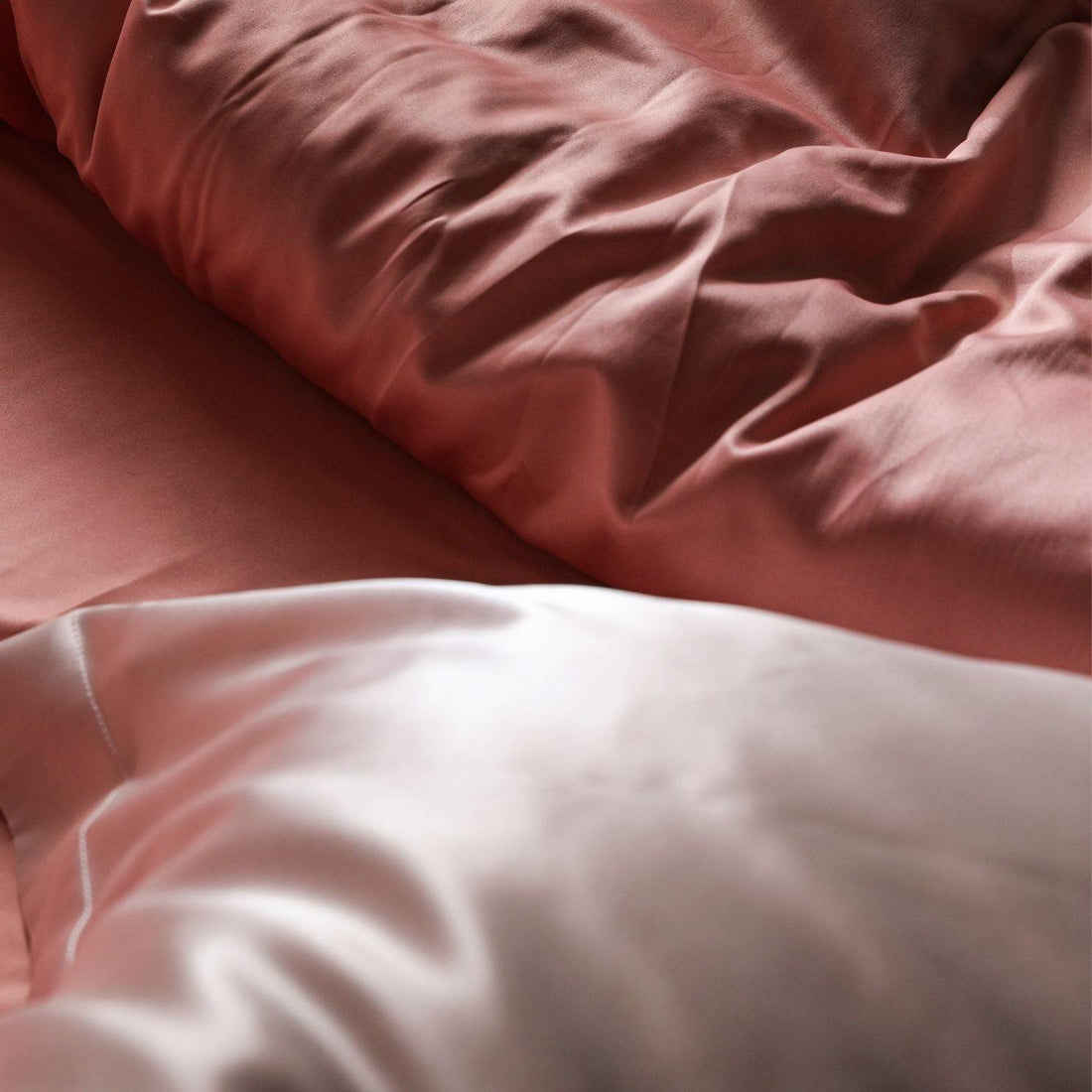 Close-up of a luxurious pink and white silk pillowcase, designed to protect starter locs and reduce hair breakage while sleeping.